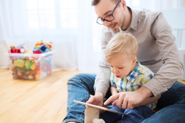 koncepcja rodziny, dzieciństwa, ojcostwa, technologii i ludzi - szczęśliwy ojciec i syn z komputerem typu tablet PC grającym w domu