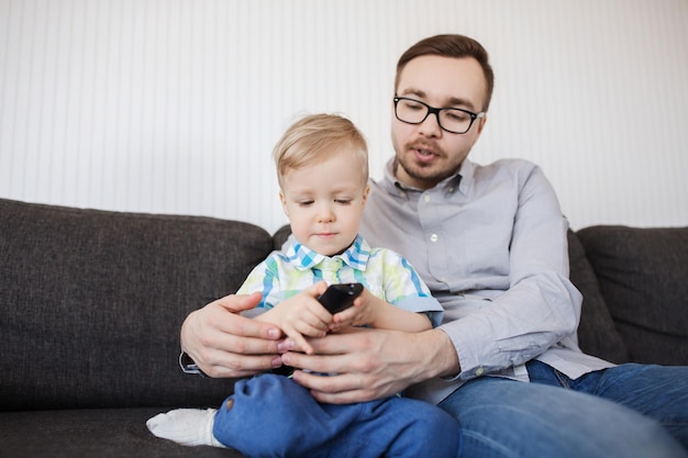 koncepcja rodziny, dzieciństwa, ojcostwa, technologii i ludzi - szczęśliwy ojciec pomaga synkowi z pilotem i oglądaniem telewizji w domu