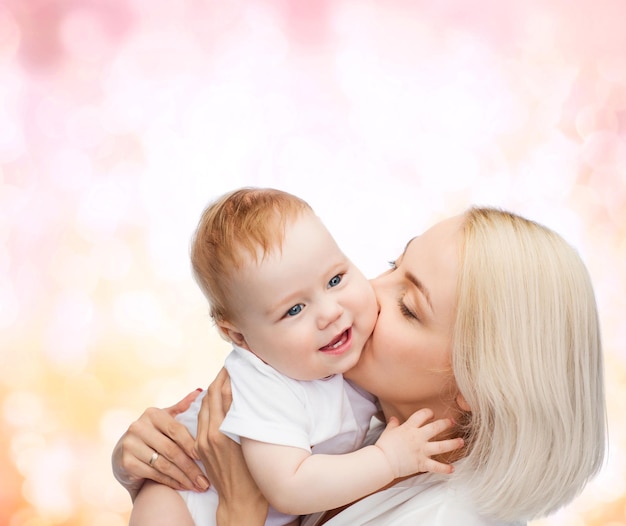 Koncepcja rodziny, dziecka i rodzicielstwa - szczęśliwa matka całuje uśmiechnięte dziecko
