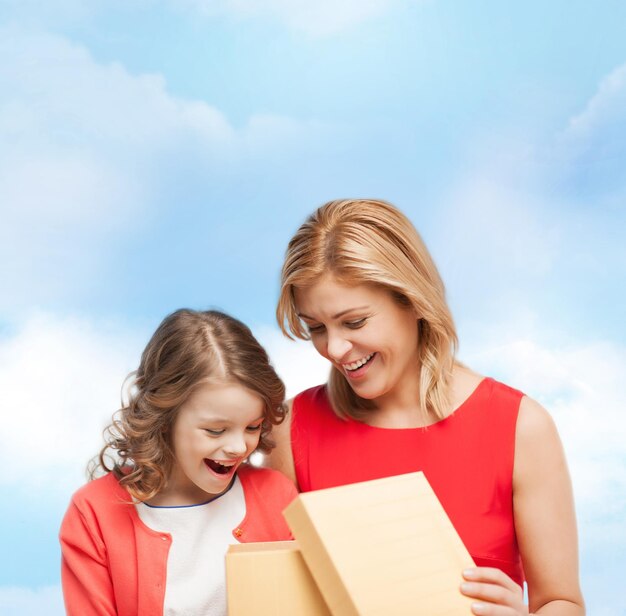 koncepcja rodziny, dziecka, wakacji i przyjęcia - uśmiechnięta matka i córka z pudełkiem prezentowym