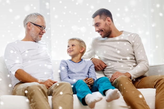 koncepcja rodziny, szczęścia, pokolenia i ludzi - uśmiechnięty ojciec, syn i dziadek siedzą na kanapie w domu