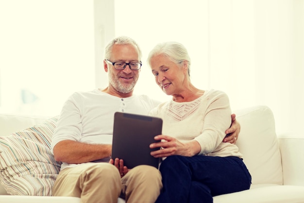 koncepcja rodziny, technologii, wieku i ludzi - szczęśliwa para starszych z komputerem typu tablet w domu