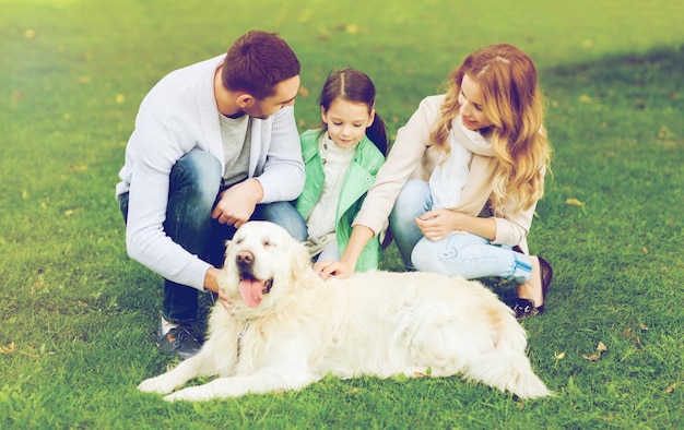 koncepcja rodziny, zwierząt domowych, zwierząt domowych i ludzi - szczęśliwa rodzina z psem labrador retriever na spacerze w letnim parku