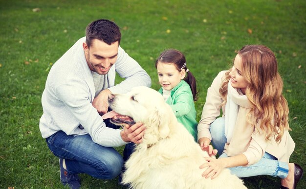 koncepcja rodziny, zwierząt domowych, zwierząt domowych i ludzi - szczęśliwa rodzina z psem labrador retriever na spacerze w parku