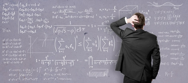 Koncepcja samokształcenia z widokiem z tyłu na mężczyznę w czarnym garniturze przed tablicą uczelni z równaniami matematycznymi