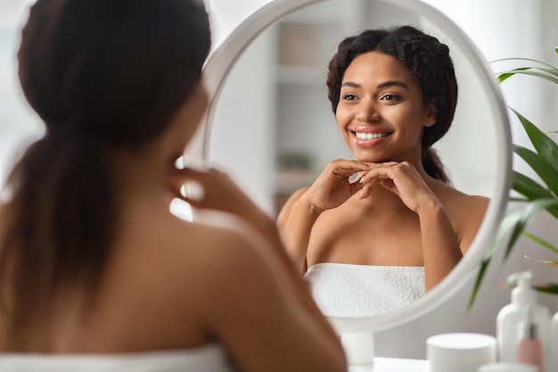 Koncepcja samoopieki piękna młoda Afroamerykanka patrząca w lustro w domu