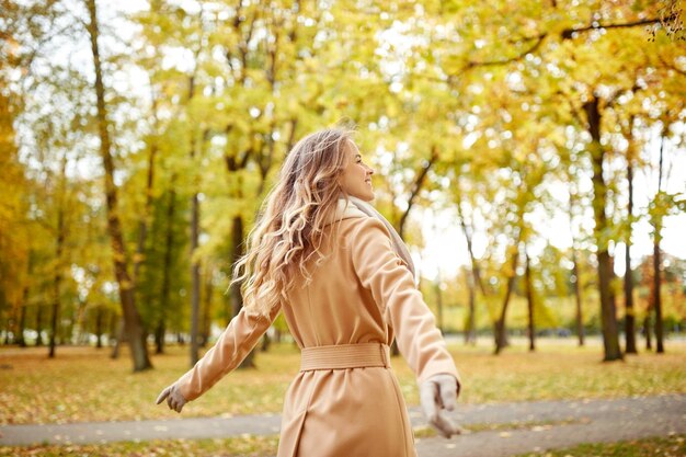 koncepcja sezonu i ludzi - piękna szczęśliwa młoda kobieta spacerująca w jesiennym parku