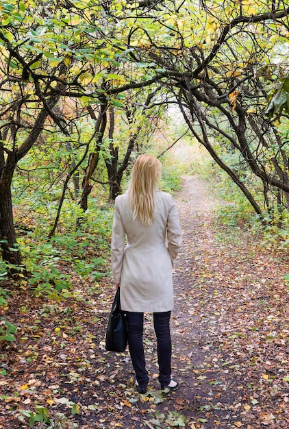 Koncepcja sezonu jesiennego. Samotna kobieta w jasnym jesiennym lesie Widok z tyłu
