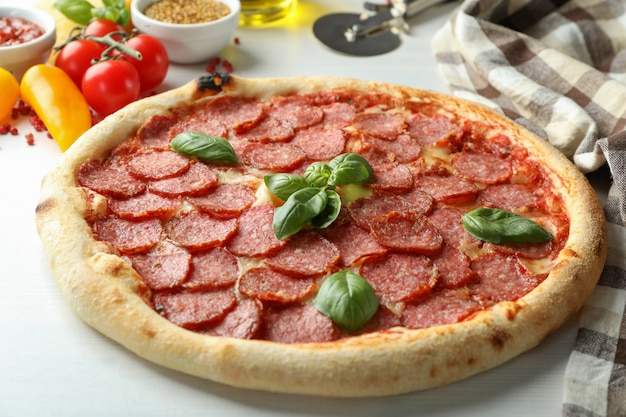 Koncepcja smacznego jedzenia z pizzą salami na białym drewnianym tle