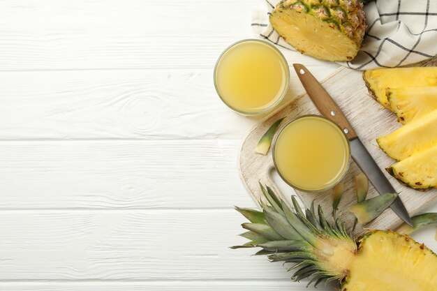 Koncepcja śniadanie z ananasem i szklanki z sokiem na drewnianym stole, widok z góry