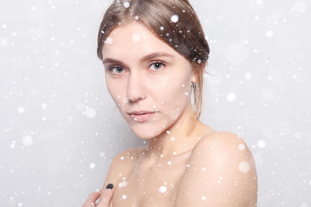 Koncepcja śniegu, zimy, bożego narodzenia, piękna, pielęgnacji skóry i ludzi - Kobieta Spa. Piękna Dziewczyna Po Kąpieli Dotyka Jej Twarzy. Piękna pani z ręcznikiem na głowie, dotykając jej miękkiej skóry. na tle śniegu