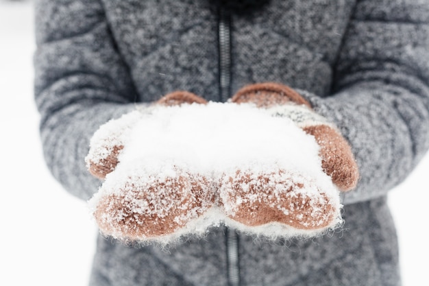 Koncepcja spacerów, pory roku i ludzi - szczęśliwa młoda kobieta trzyma śnieg w winter park