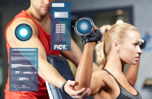 Zdjęcie koncepcja sportu, fitness, kulturystyki i ludzi - mężczyzna i kobieta z hantlami napinającymi mięśnie na siłowni nad wirtualnymi wykresami