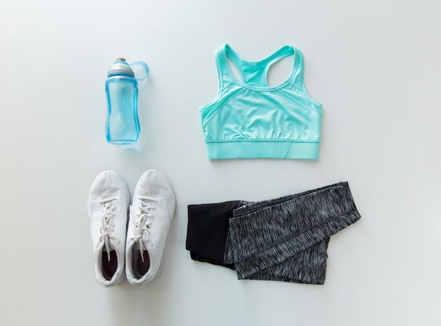 koncepcja sportu, fitness, zdrowego stylu życia i przedmiotów - zbliżenie kobiecej odzieży sportowej i zestawu butelek