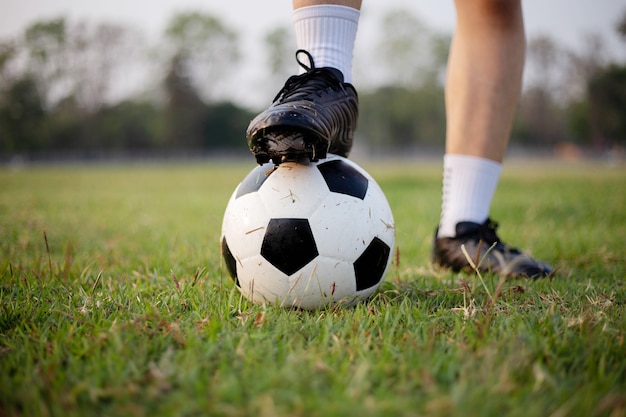 Koncepcja sportu i rekreacji męski piłkarz ubrany w czarną koszulkę i spodnie uprawiający kopanie piłki na trawiastym boisku.