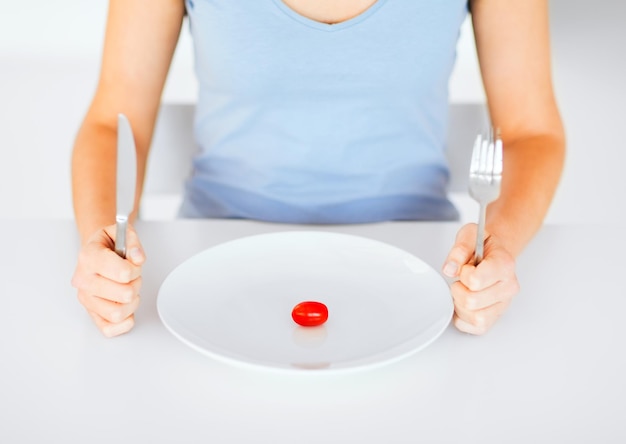 koncepcja sportu, opieki zdrowotnej i diety - kobieta z talerzem i jednym pomidorem
