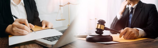 Koncepcja sprawiedliwości i prawaSędzia w sali sądowej z młotkiem pracującym z komputerem i dokującą klawiaturą okularów na stole w porannym świetle