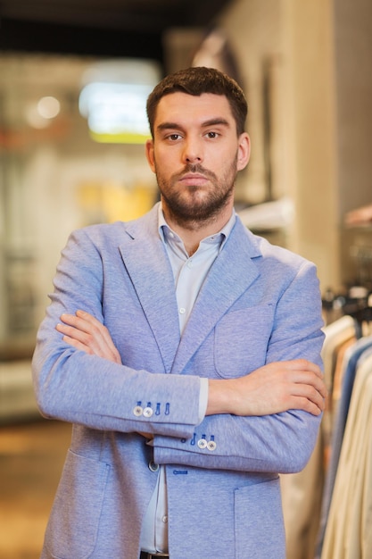 koncepcja sprzedaży, zakupów, mody, stylu i ludzi - młody przystojny mężczyzna w kurtce w sklepie odzieżowym