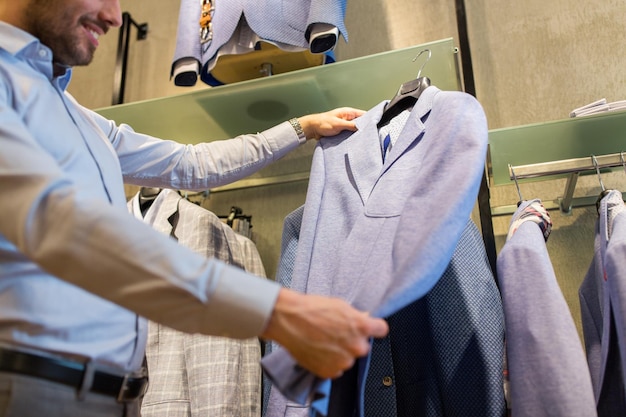 koncepcja sprzedaży, zakupów, mody, stylu i ludzi - zbliżenie mężczyzny wybierającego kurtkę w sklepie odzieżowym