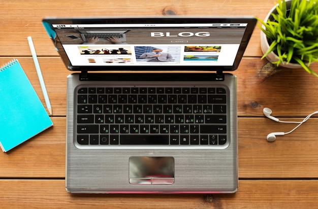 koncepcja środków masowego przekazu, internetu, biznesu i technologii - zbliżenie laptopa ze stroną internetową bloga na ekranie na drewnianym stole