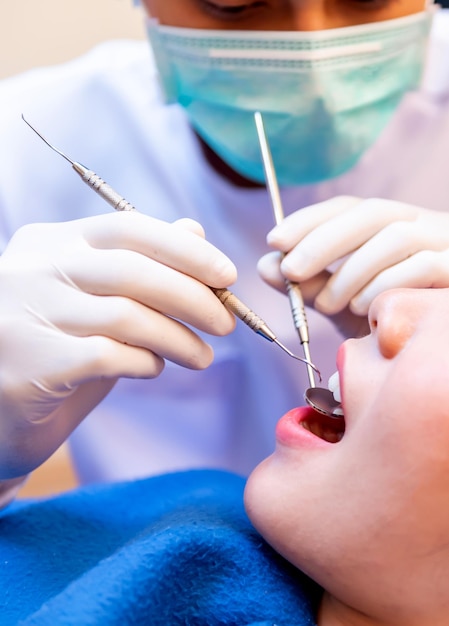 Koncepcja stomatologii i opieki zdrowotnej w klinice dentystycznej. Lekarz dentysta kontrolna zębów dla młodej pacjentki azjatyckiej.