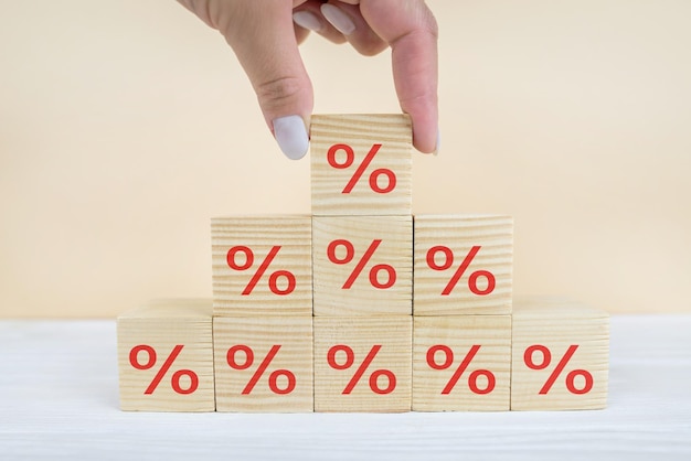 Koncepcja stóp procentowych finansowych i hipotecznych Ręczne umieszczanie bloku drewnianego kostki rosnącego na górze z ikoną symbolu procentowego w kierunku w górę