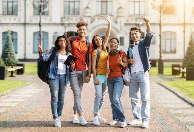 Koncepcja studencka grupa szczęśliwych wieloetnicznych studentów z zeszytami ćwiczeń pozujących razem na świeżym powietrzu