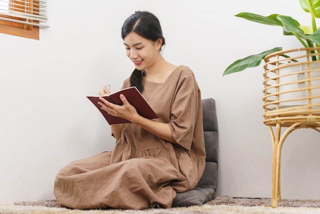 Koncepcja stylu życia relaksu Młoda Azjatycka kobieta pisze na notebooku siedząc w salonie