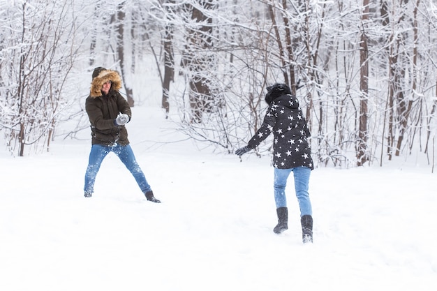 Koncepcja stylu życia, sezonu i wypoczynku - zabawna para gra w snowball w winter park.