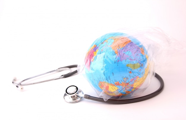Zdjęcie koncepcja światowego dnia środowiska. ziemia w plastikowej torbie ze stetoskopem na białym tle