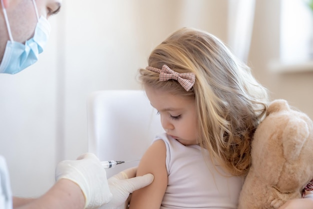 Koncepcja szczepień dla dzieci Szczęśliwa mała urocza blondynka trzyma zabawkę i dostaje grypę