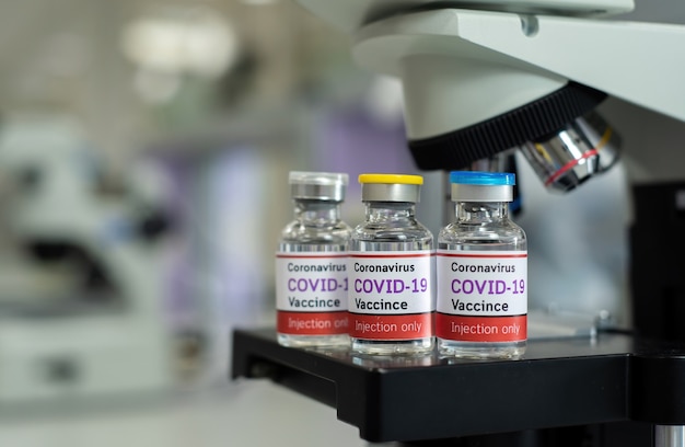 Koncepcja szczepionki przeciwko koronawirusowi COVID-19, mikroskopijna I butelka szczepionki przeciwko COVID-19 W laboratoriach medycznych