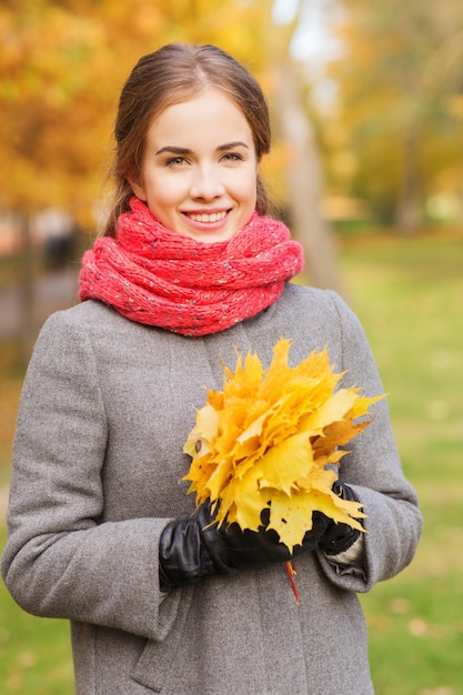koncepcja szczęścia, pory roku i ludzi - uśmiechnięta kobieta z bukietem liści w jesiennym parku