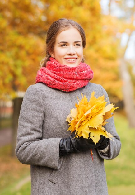 koncepcja szczęścia, pory roku i ludzi - uśmiechnięta kobieta z bukietem liści w jesiennym parku