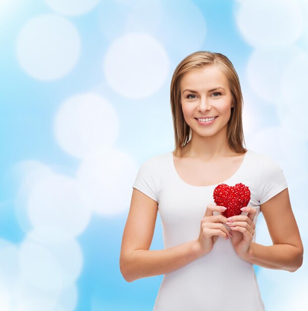 Zdjęcie koncepcja szczęścia, zdrowia i miłości - uśmiechnięta kobieta w białej koszulce z sercem