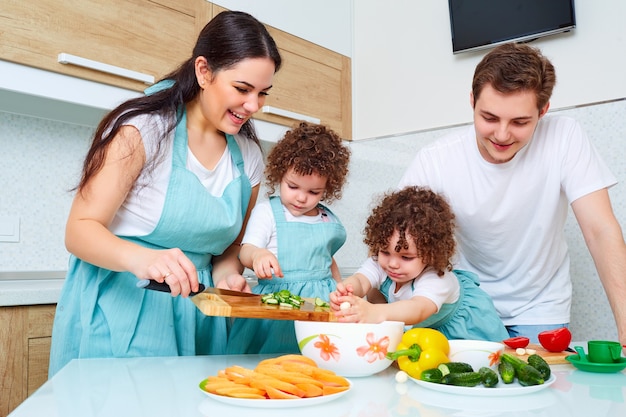 Koncepcja szczęśliwej rodziny dziewczyny bliźniaki matka ojciec i córka bliźniaki vegitarianskuyu przygotowują posiłki w kuchni szczęście śmiech i uśmiechy