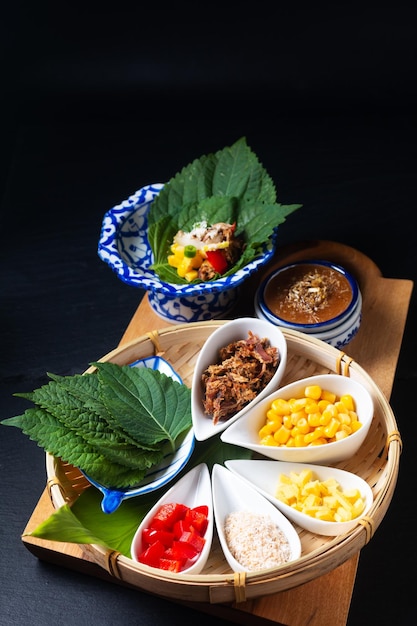 Koncepcja tajskiego jedzenia Fusion Tajska przekąska ziołowa i tuńczykowa Miang Kham okład z jednym kęsem przez perilla leaveshiso z mieszanką ziół sos z cukru kokosowego na czarnym tle z miejscem na kopię