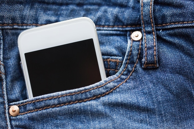 koncepcja technologii i komunikacji - smartfon w kieszeni dżinsowych spodni lub dżinsów