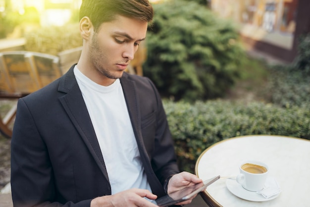 Koncepcja technologii i komunikacji Stylowy kaukaski student surfujący po Internecie na cyfrowym tablecie, korzystający z bezpłatnego połączenia bezprzewodowego w kawiarni podczas przerwy na kawę Przystojny mężczyzna wysyłający wiadomości online