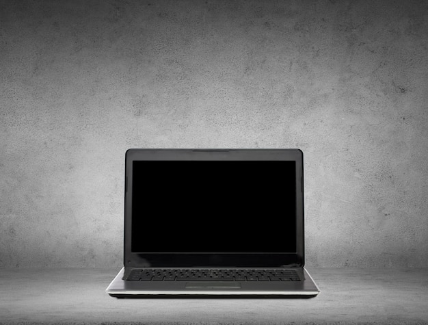 koncepcja technologii i reklamy - laptop z czarnym pustym ekranem na szarym betonowym tle