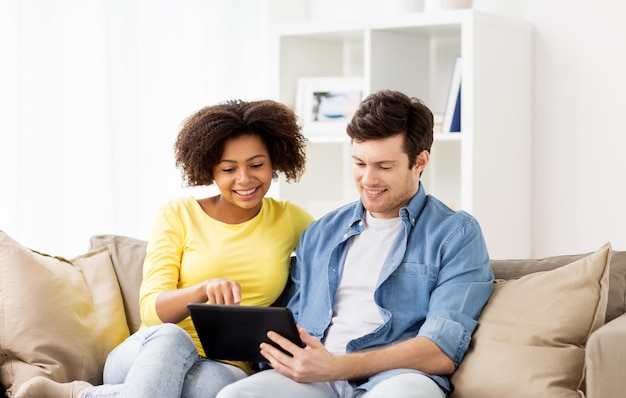 Koncepcja technologii, internetu i ludzi - uśmiechnięta szczęśliwa para z tabletem w domu