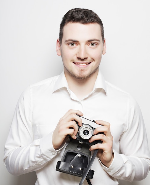 Koncepcja technologii, ludzi i stylu życia: młody fotograf na białym tle