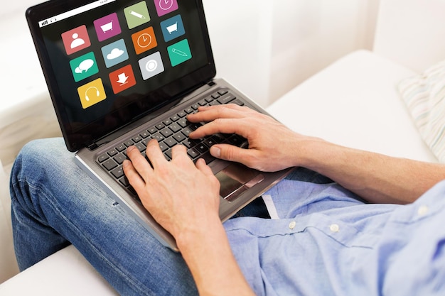 koncepcja technologii, mediów, ludzi i stylu życia - zbliżenie męskich rąk pisania na laptopie z ikonami menu na ekranie w domu