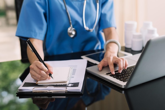 Koncepcja technologii medycznej Lekarz pracujący z telefonem komórkowym i stetoskopem oraz laptopem z cyfrowym tabletem w nowoczesnym biurze w szpitalu w porannym świetle