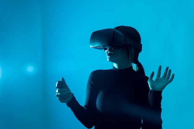 Koncepcja technologii Metaverse Kobieta w okularach wirtualnej rzeczywistości VR na niebieskim tle Futurystyczny styl życia