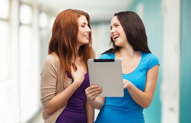 koncepcja technologii, przyjaźni i ludzi - dwoje uśmiechniętych nastolatków wskazujących palcem ekran tabletu i patrzących na siebie