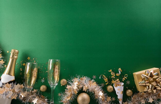 Koncepcja tło uroczystość szczęśliwego nowego roku. Szampan z kieliszkiem, złotą wstążką, gwiazdami i bombką na zielonym tle.
