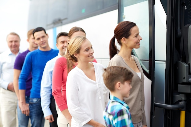 koncepcja transportu, turystyki, podróży i ludzi - grupa szczęśliwych pasażerów wsiadających do autobusu podróżnego