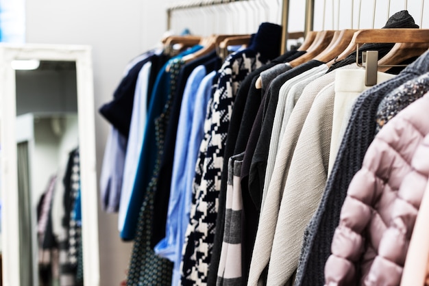 Koncepcja trendu mody. Ciepła zimowa kolekcja odzieży damskiej z dzianinowymi wełnianymi sweterkami na drewnianych wieszakach.