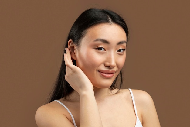 Koncepcja twarzy Spa Piękna młoda koreańska dama dotyka jej miękkiej skóry na policzku, ciesząc się wynikiem zabiegów kosmetycznych